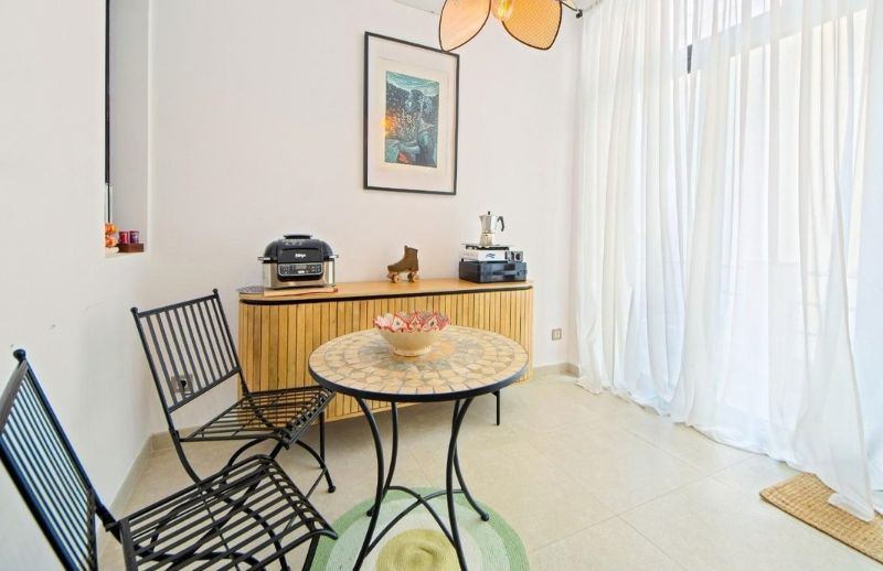 Cozy breakfast nook with mosaic table and iron chairs in Palma.