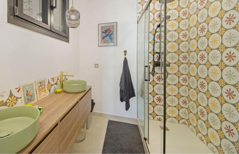 Renovated bathroom with dual green basins and hydraulic tiles in Palma.