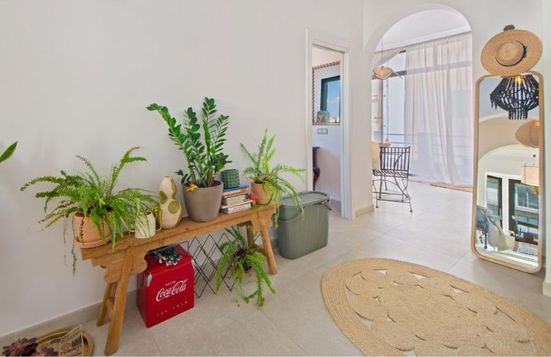 Spacious entrance hallway with archways, plants, and jute rug in Palma.