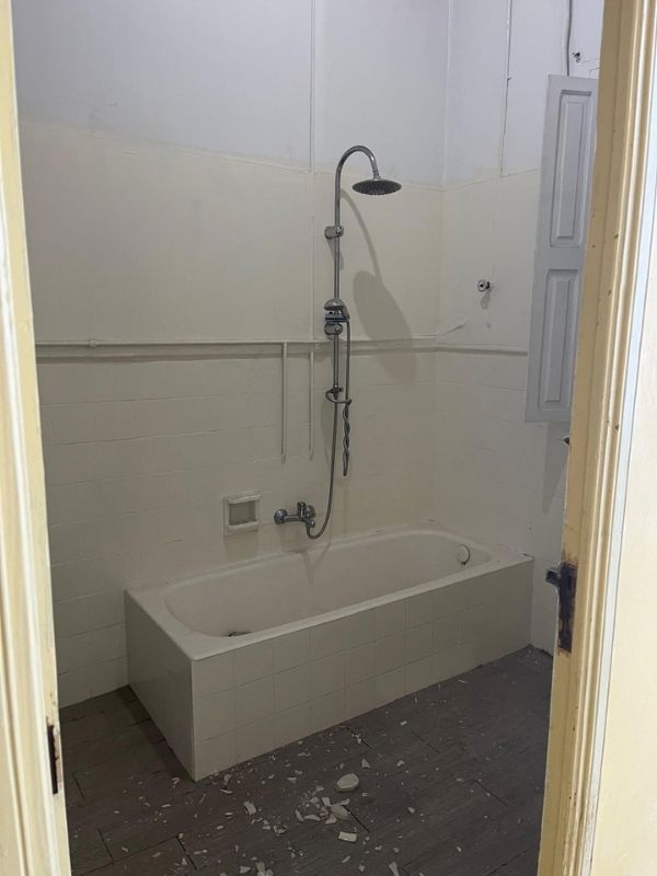 Obsolete bathroom with old bathtub and exposed piping prior to renovation in Palma for BuildWell Mallorca