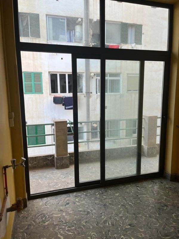 Outdated balcony entrance and sliding doors before home renovation in Palma